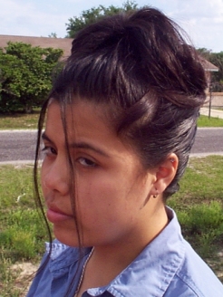 A head and shoulder shot of Elysia's hair up swept hair style with two thin long wisps of hair hanging softly down on either side of her face.  Elysia is outside, and frowing with impatience at being photographed. (67535 bytes)